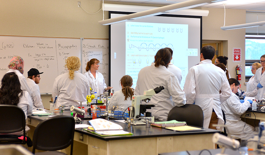 Students in lab coats gathered to watch a demonstration.